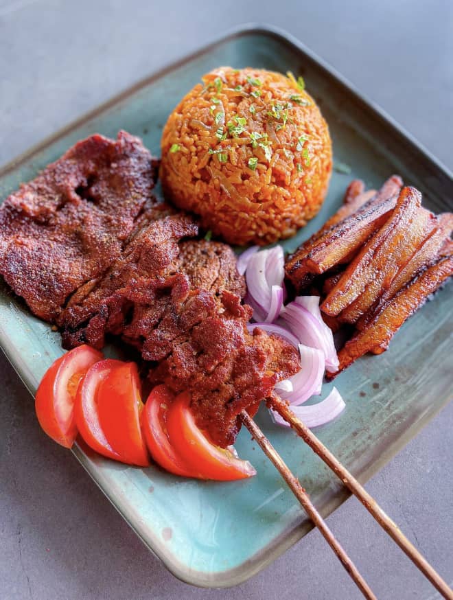 A full plate of Nigerian party jollof with suya and fried plantain